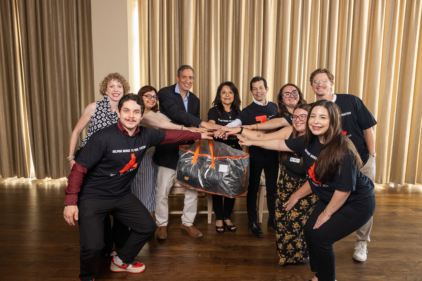 Team members kneeling and posing playfully around the donation bag