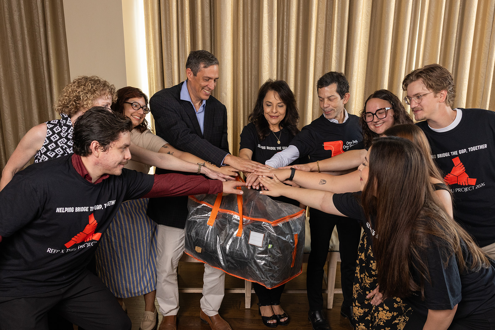 Team members reaching in together over a duffel bag of donated items