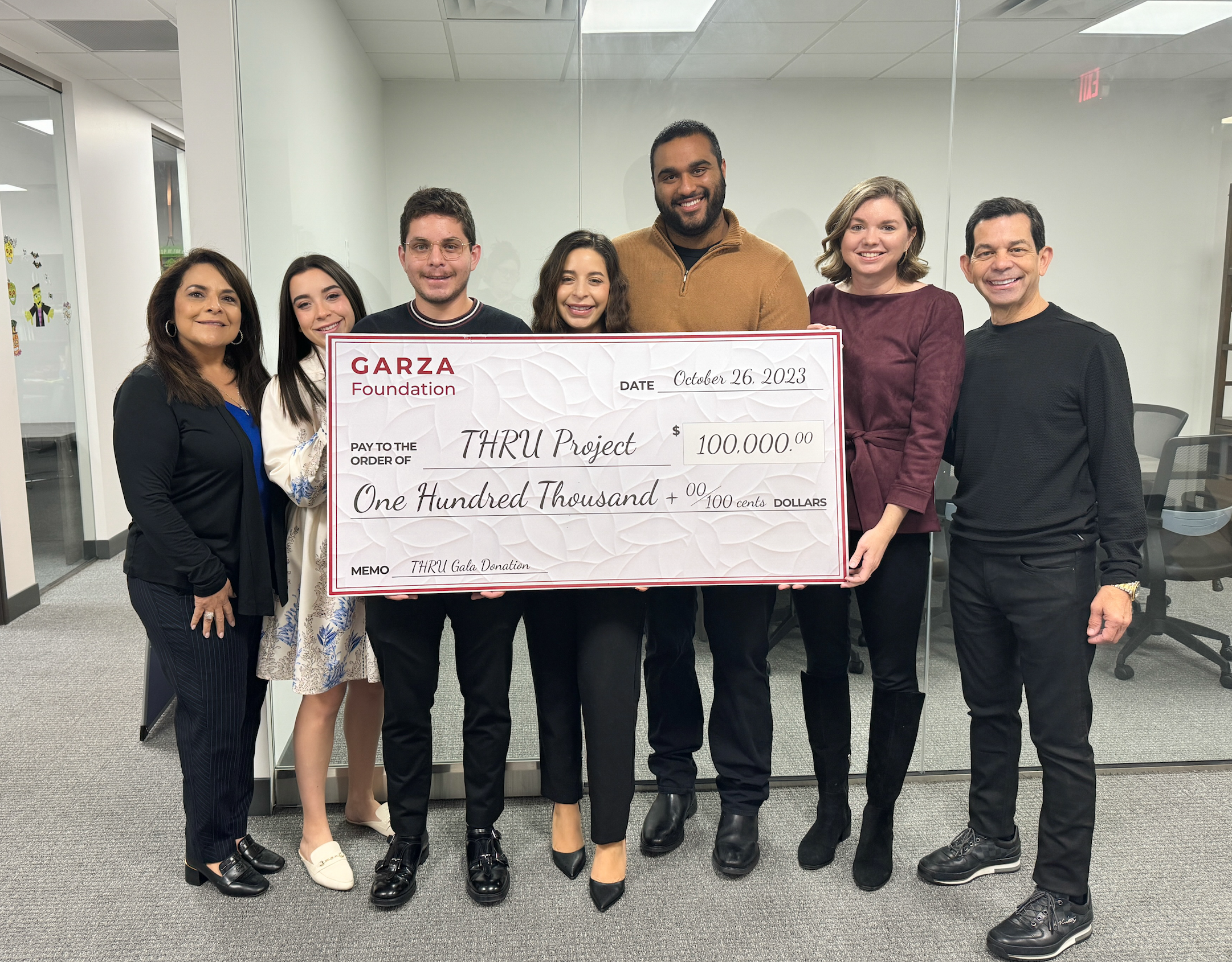 The Garza family and THRU Project team holding a donation check